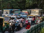 Busy urban traffic with buses, motorcycles, and pedestrians in a city street