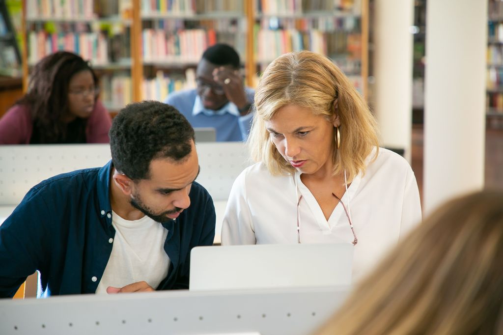 People collaborating on a laptop in a library